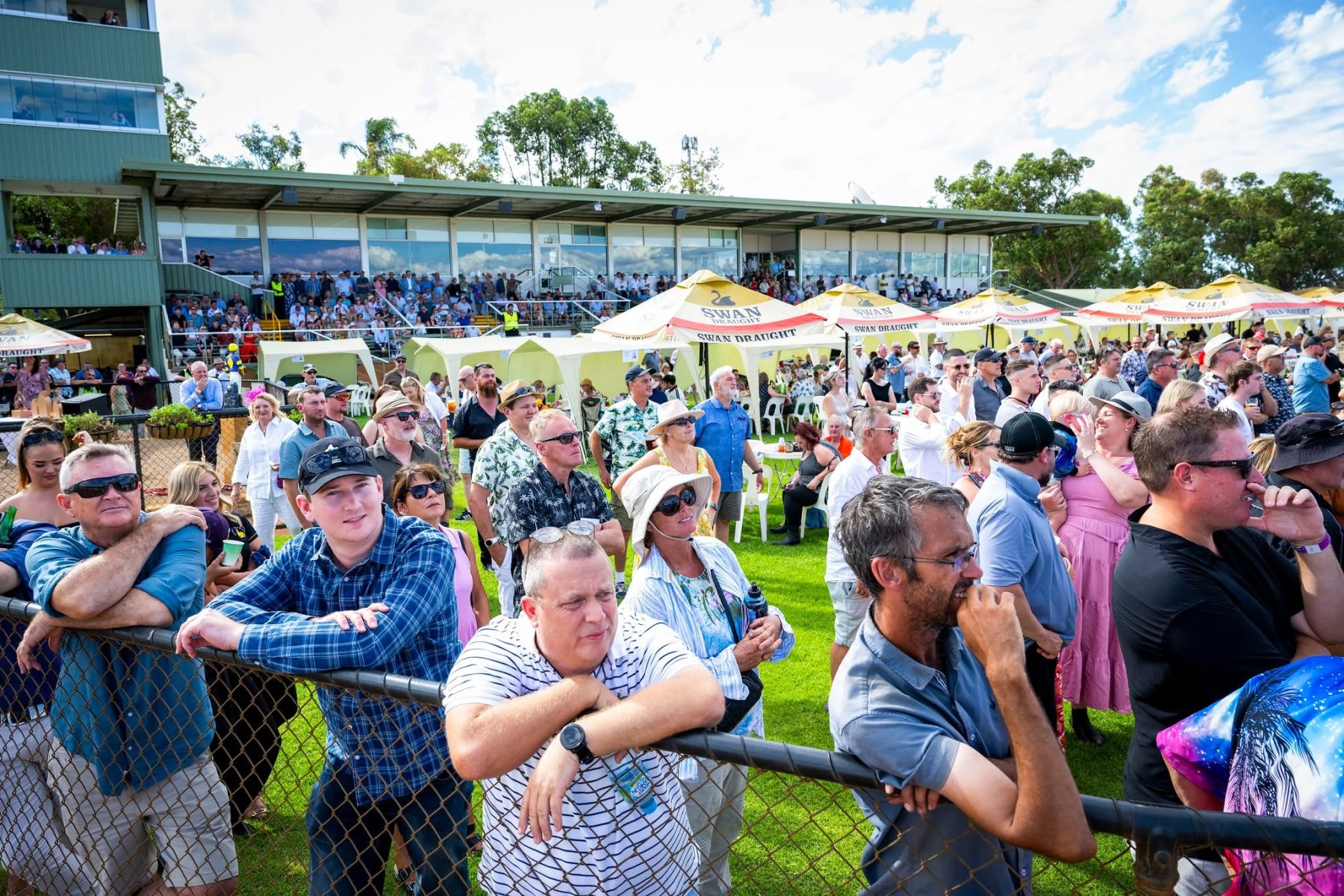 Racegoers at the rail in front of the grandstand